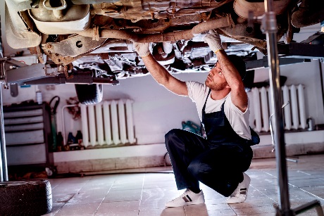 A technician working on the underside of a vehicle