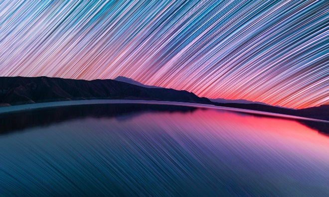 A watery landscape with a time lapse of the night sky