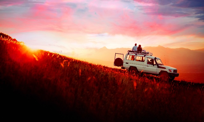 A couple sitting on a parked vehicle looking toward a bright future