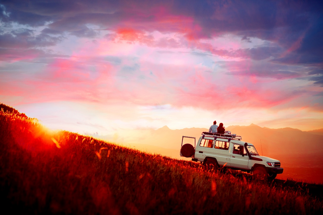 A couple sitting on a parked vehicle looking toward a bright future