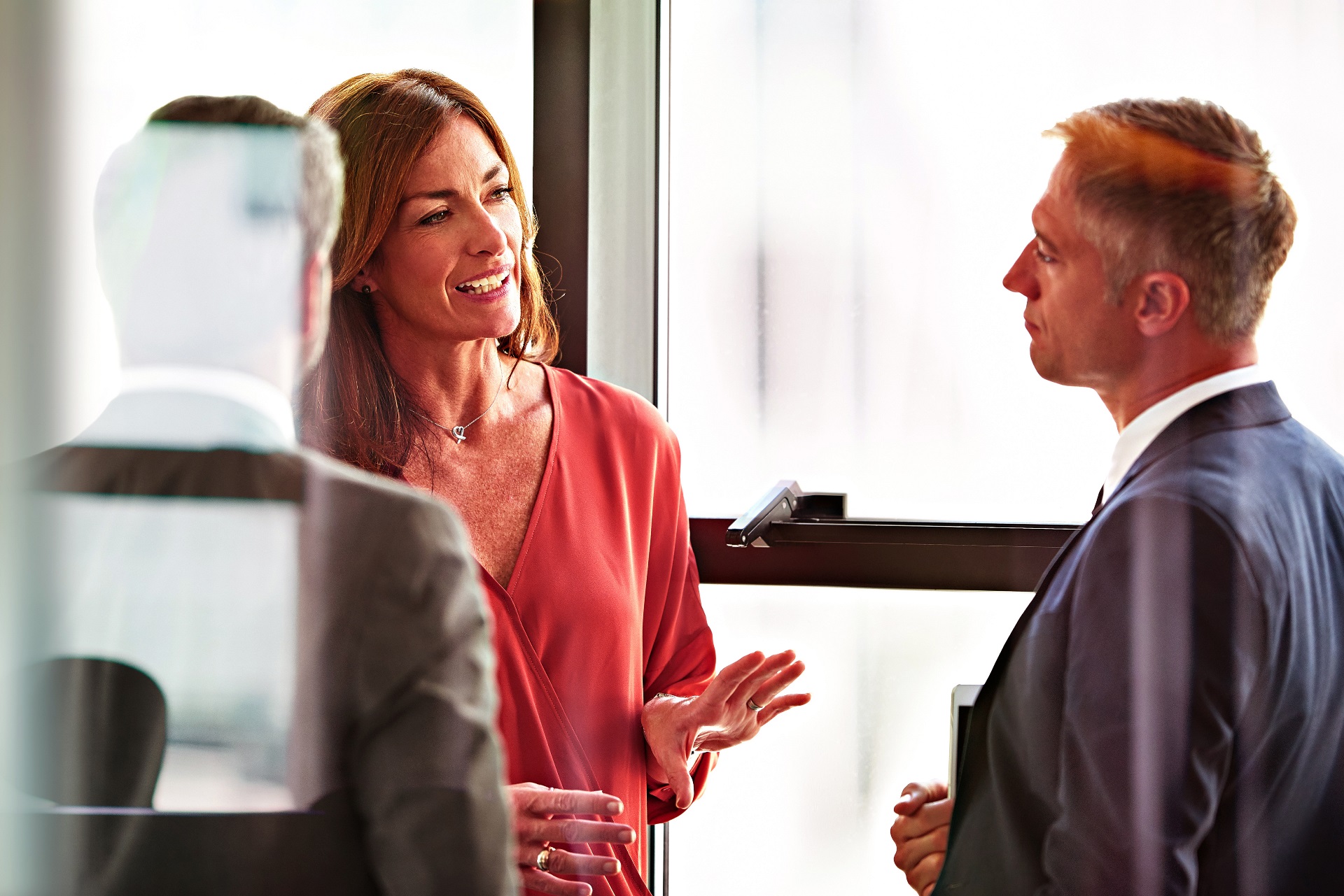 A small group of well-dressed people talking in a bright room