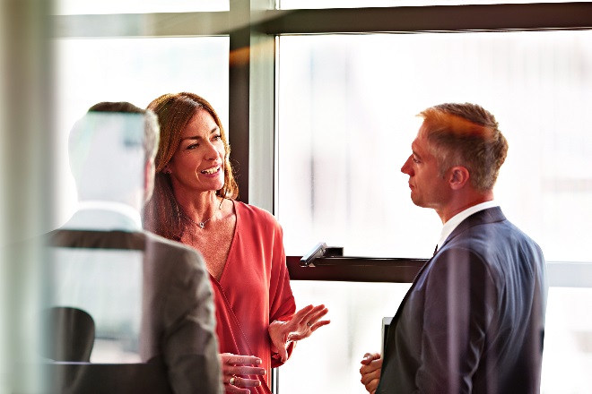 A small group of well-dressed people talking in a bright room