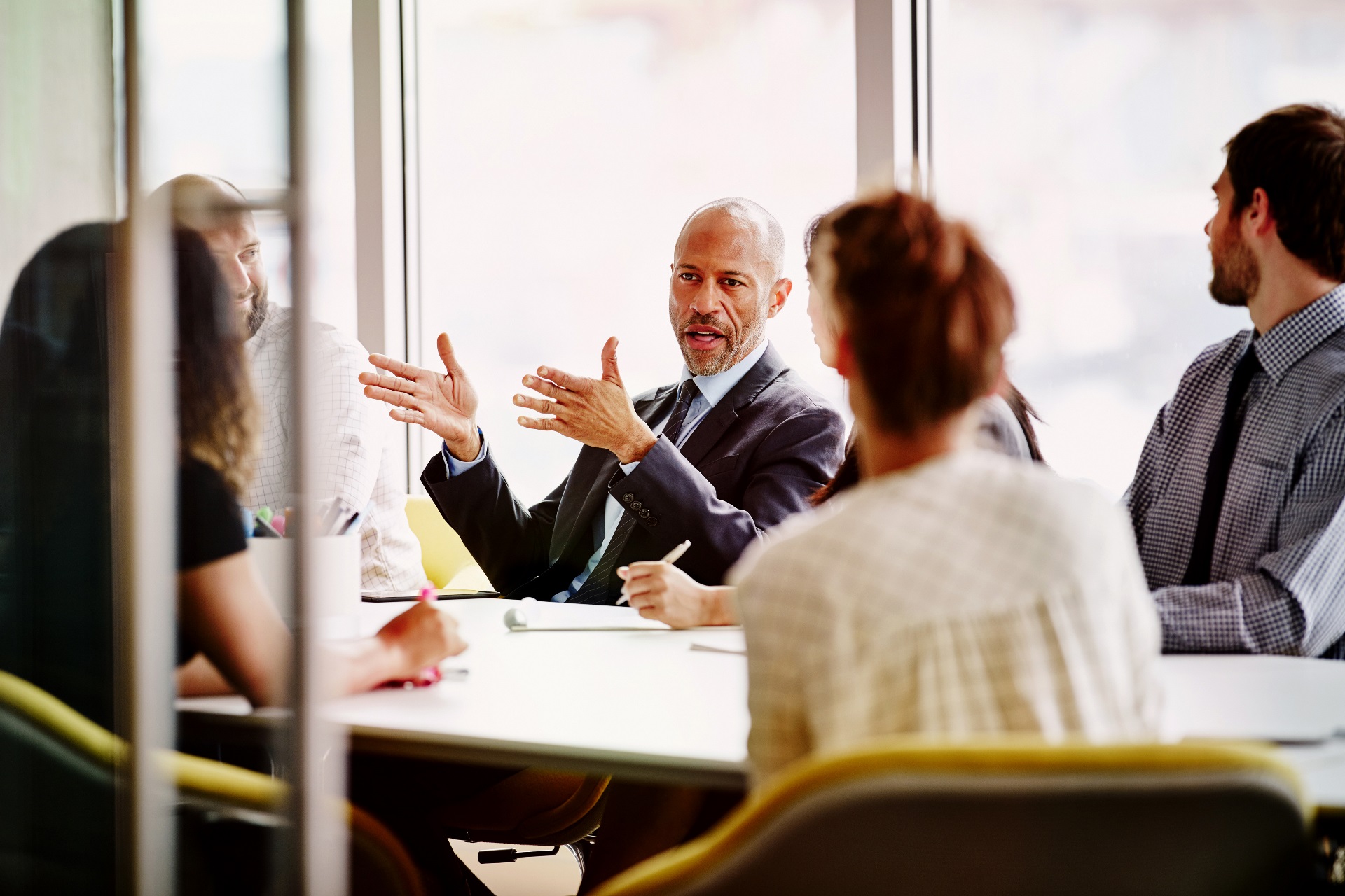 A team sits in a bright room around a table discussing business