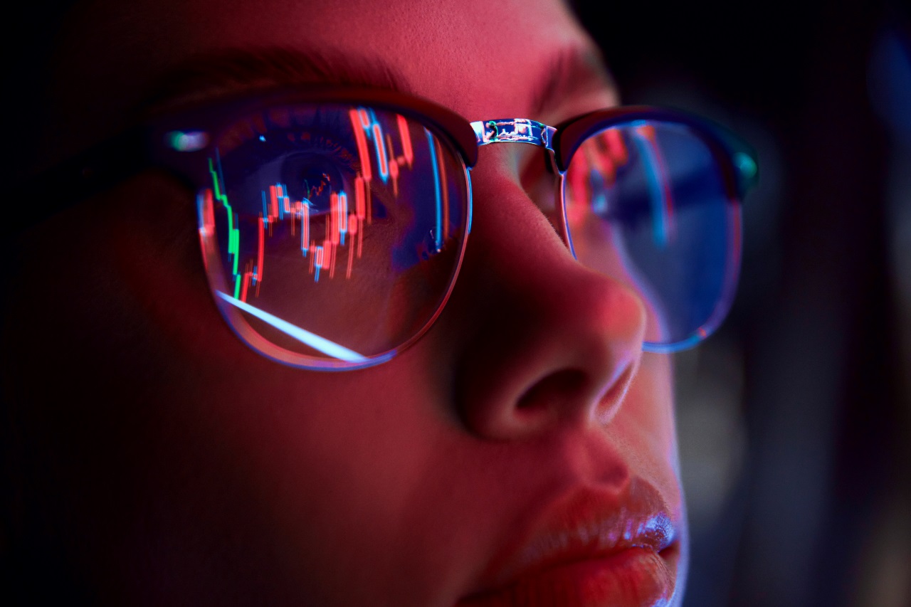 Close-up of a person wearing glasses with stocks reflected in the lenses