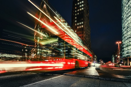 A red bus driving through a city at night