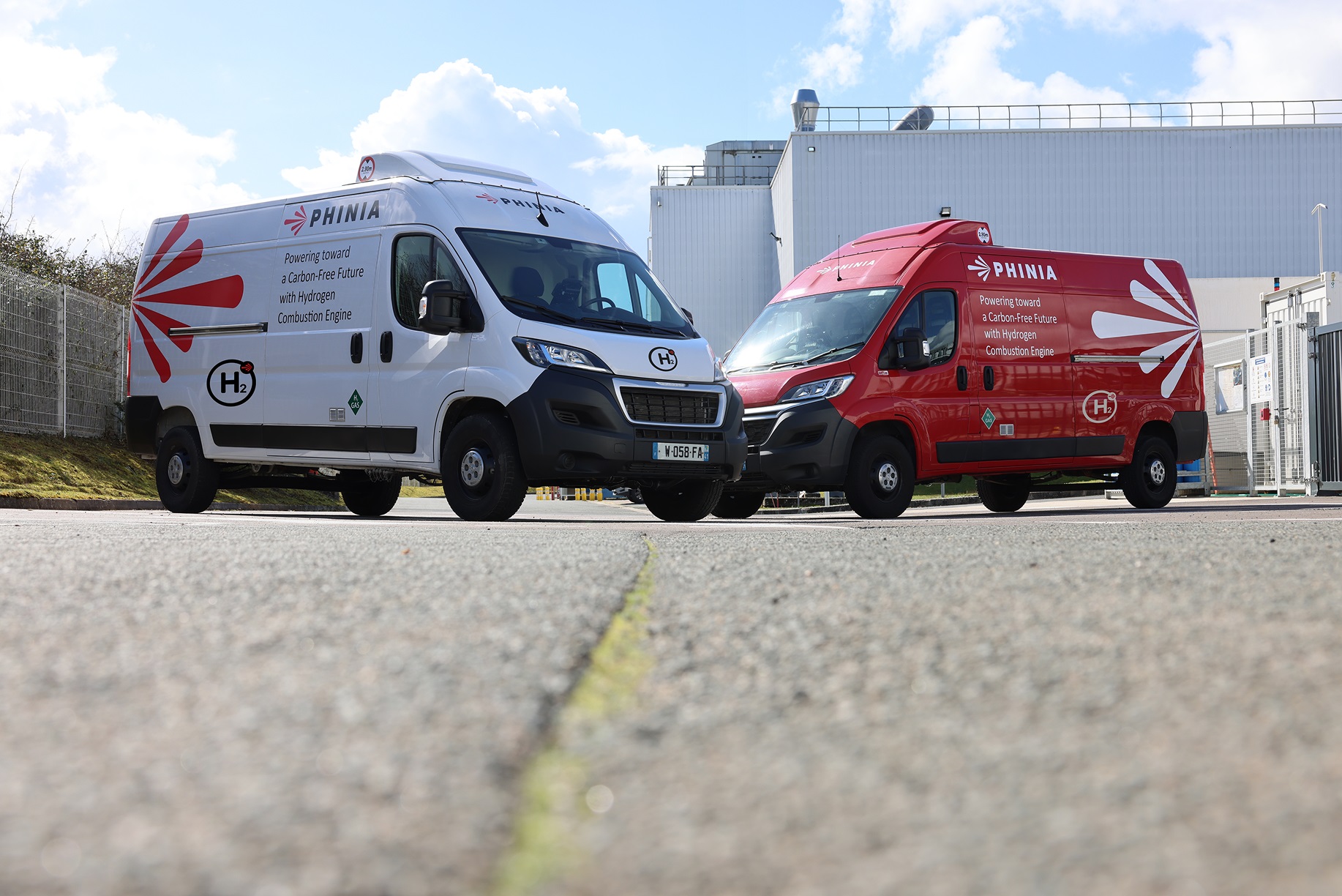 PHINIA-branded hydrogen vans parked outside an industrial facility.