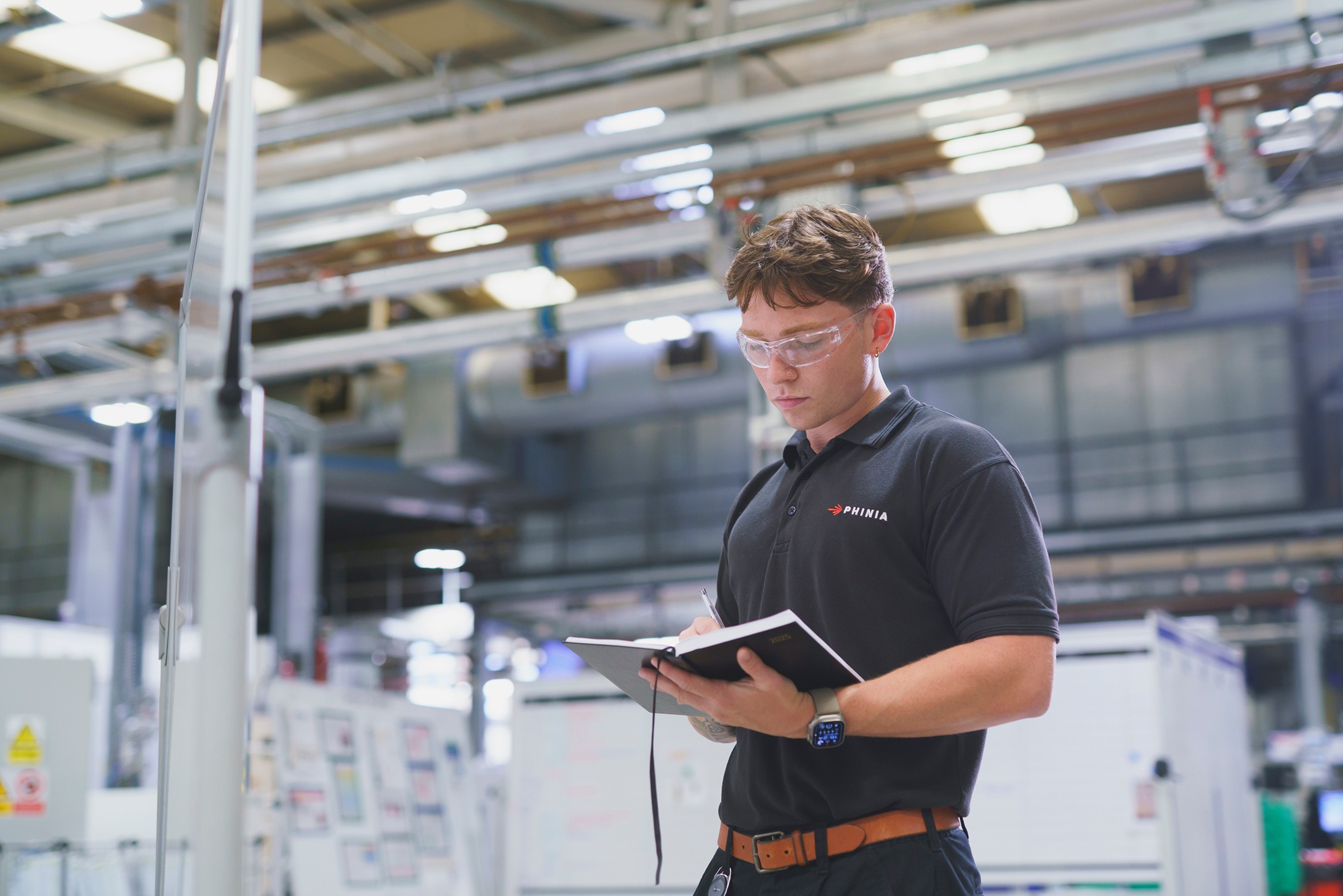 Engineer writing inspection notes down inside a factory.