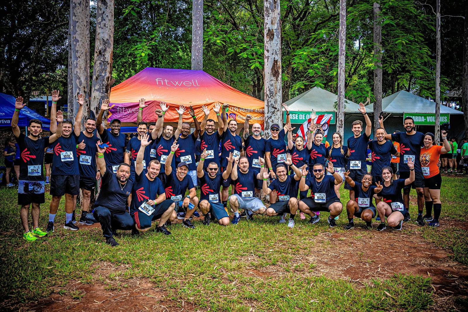 Group of runners from Phinia team posing at an outdoor charity run event under colorful tents