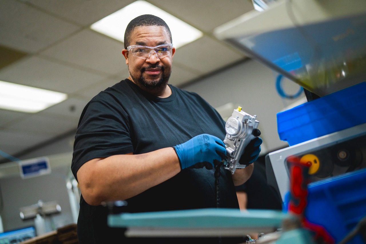 Factory technician assembling a high-precision automotive component in a modern industrial workshop, highlighting advanced engineering processes.